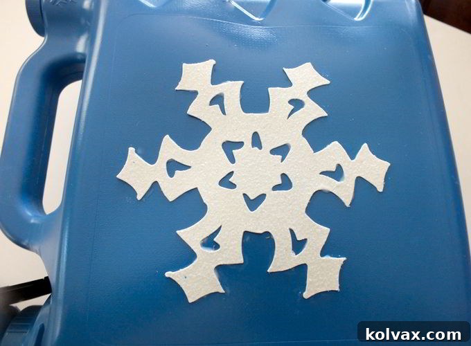 Decorating the freshly painted blue bubble dispenser with paper snowflakes for a Frozen theme