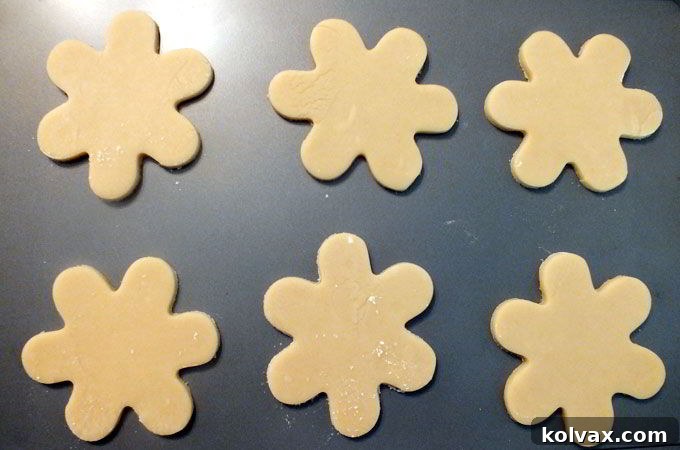 Freshly cut snowflake cookies arranged on a baking sheet, ready to be baked to golden perfection in the oven.