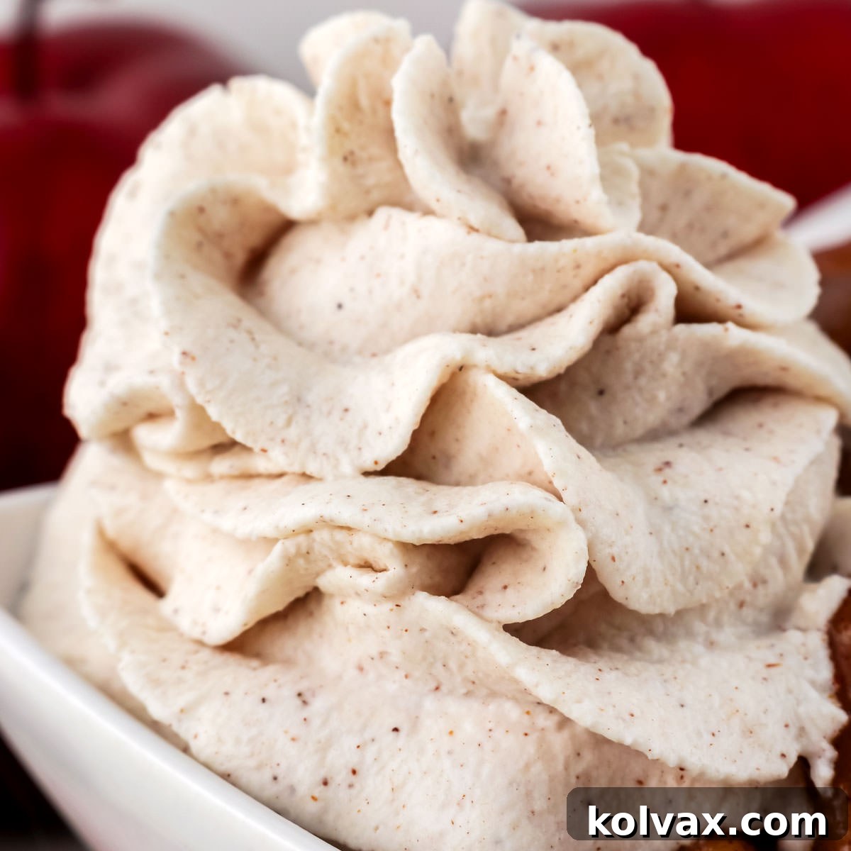 A close-up shot of a delicate dessert in a white bowl, elegantly topped with a generous, artfully swirled dollop of Homemade Cinnamon Whipped Cream.