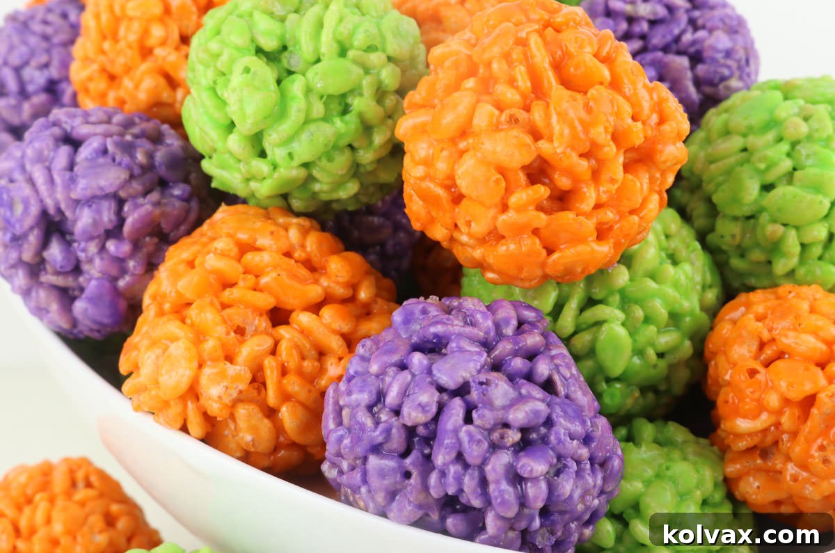 Closeup on a white serving bowl filled with Orange, Purple and Green Halloween Rice Krispie Treats Bites.