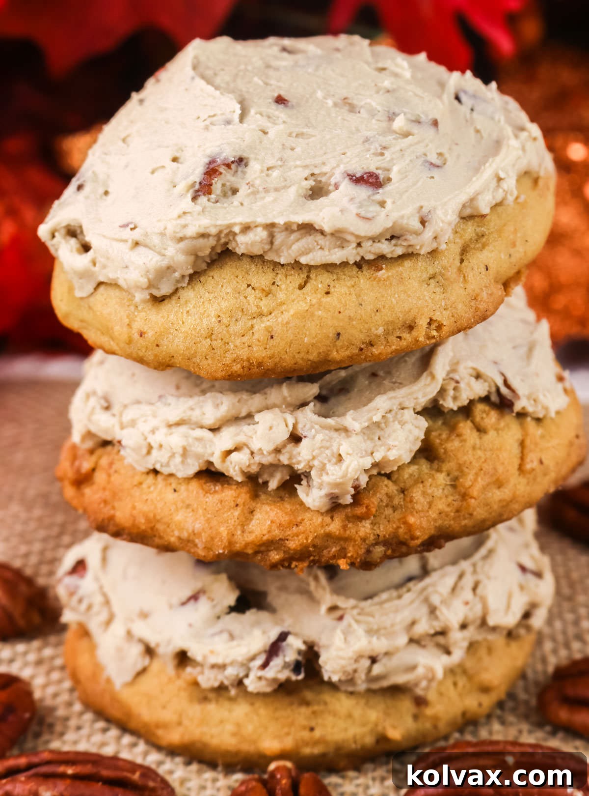 Closeup on a beautifully arranged stack of three Sweet Potato Cookies frosted with Maple Pecan Frosting, surrounded by whole pecans, highlighting their delicious appeal.