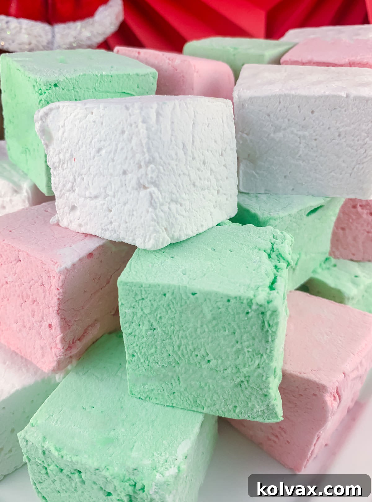 Closeup on a stack of Red, Green and White Christmas Homemade Marshmallows sitting on a white serving platter.