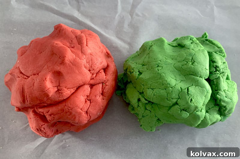 Two balls of butter cookie dough, one vibrantly colored Christmas red and the other festive green.