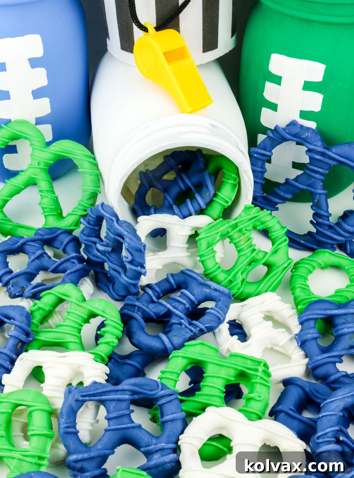 A batch of Seattle Seahawks Pretzels sprinkled on a white table next to football decorations.
