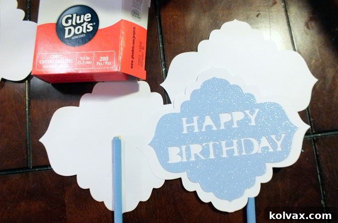 Assembling the Happy Birthday signs with glue dots and attaching them to painted balsa wood sticks for the Disney Frozen Centerpiece display.