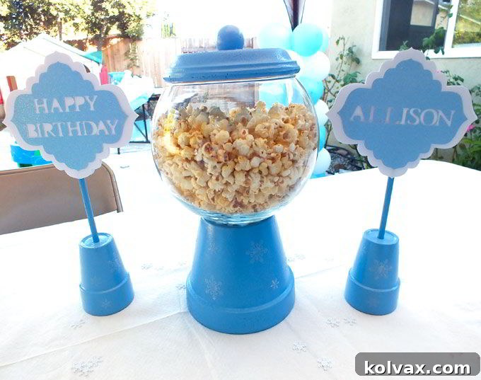 Completing the Happy Birthday signs for the Disney Frozen Centerpiece by inserting sticks into the terra cotta pot drain holes for stability.