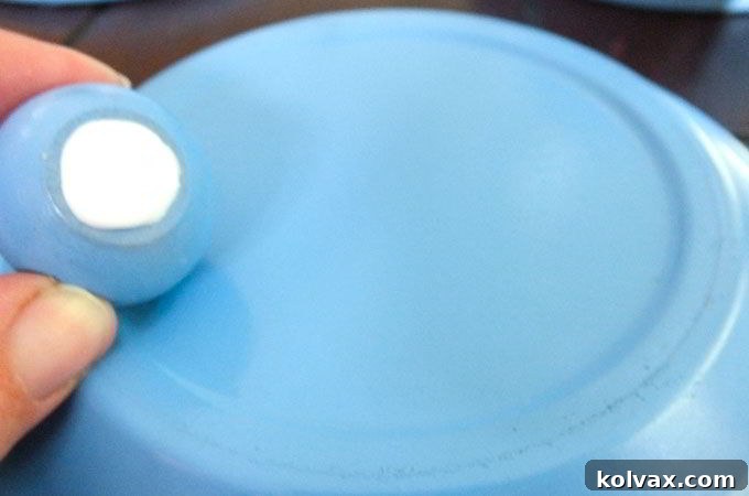 Attaching a painted wooden cabinet pull to the terra cotta pot saucer with Elmer's Glue, forming the iconic lid for the Disney Frozen Centerpiece.