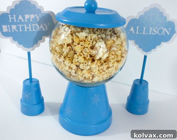 Assembled bubble gum machine style Disney Frozen Centerpiece, filled with delicious popcorn, accompanied by personalized Happy Birthday signs for a Frozen Party.