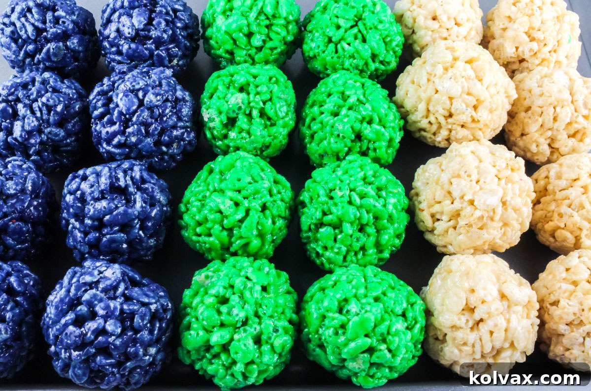 Cookie sheet filled with neat rows of Blue, Green, and White Rice Krispie Treat Bites, ready for setting.