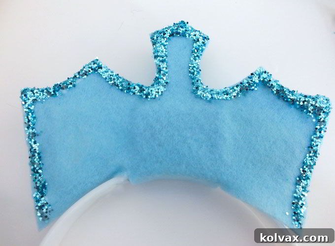 Gently tapping and brushing off excess glitter from the Elsa Crown after the glue has dried.