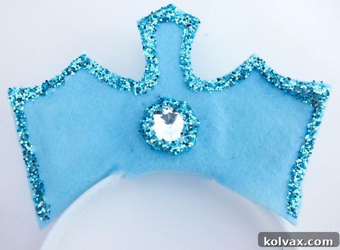 Adding a final touch of glitter in a circle around the newly attached rhinestone on the Elsa Crown.