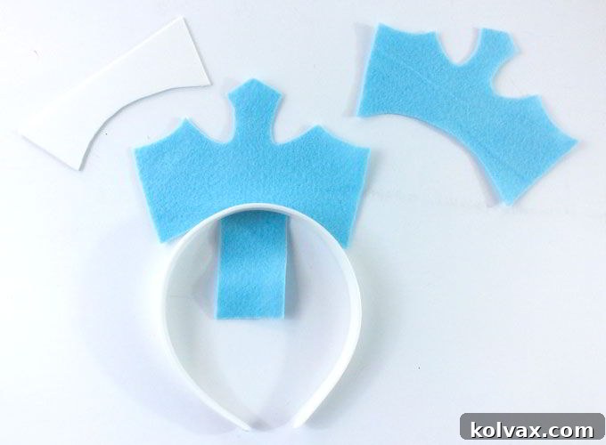 Applying hot glue to the tab of the front felt crown piece and wrapping it around the white headband for attachment.