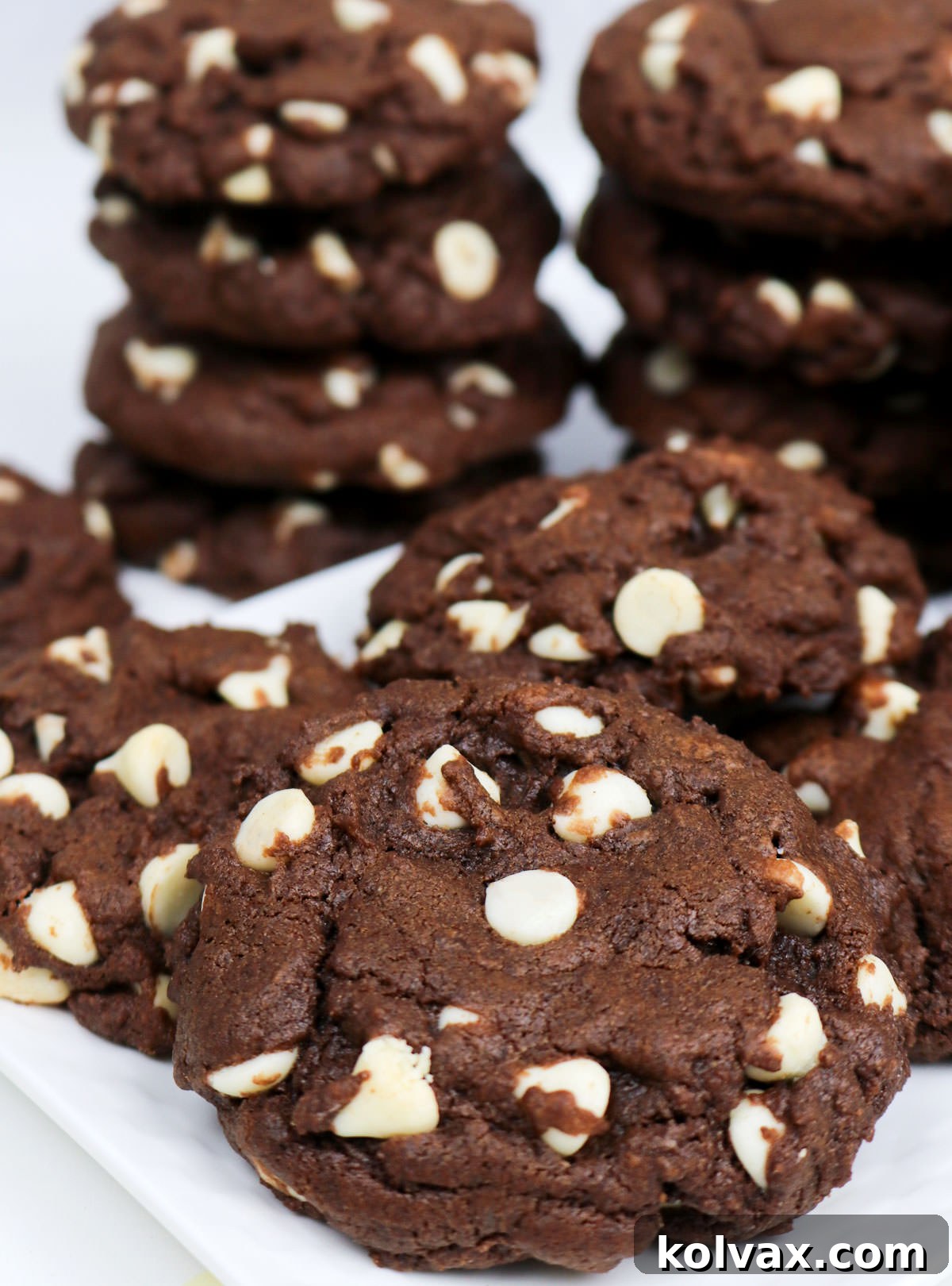 A elegant white dessert plate piled high with a generous serving of Chocolate White Chocolate Chip Cookies, perfectly baked and ready to be enjoyed.