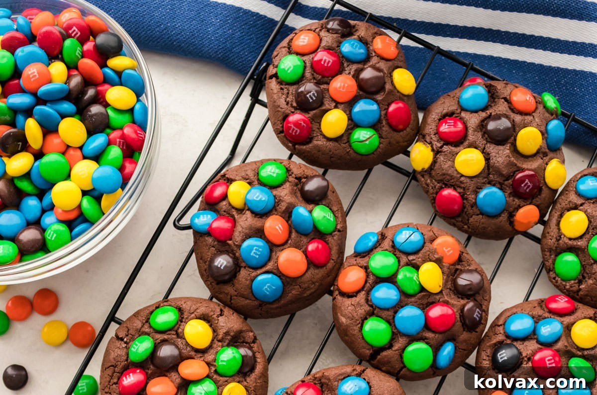 Colorful Chocolate Candy Cookies 2 An overhead shot of a fresh batch of colorful Chocolate M&M Cookies cooling on a wire rack, with a bowl of M&M candies beside them, showcasing their delicious appeal.