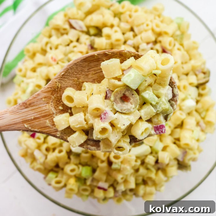 A classic, creamy Macaroni Salad in a white bowl, ready to be served. This old-fashioned recipe is perfect for any gathering.