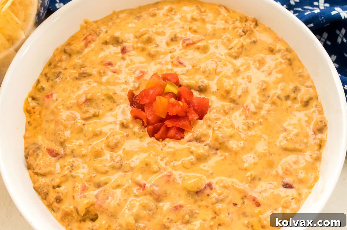 Closeup on a bowl of Rotel Dip in a white bowl with a dollop of Ro-Tel Tomatoes in the center of the bowl.