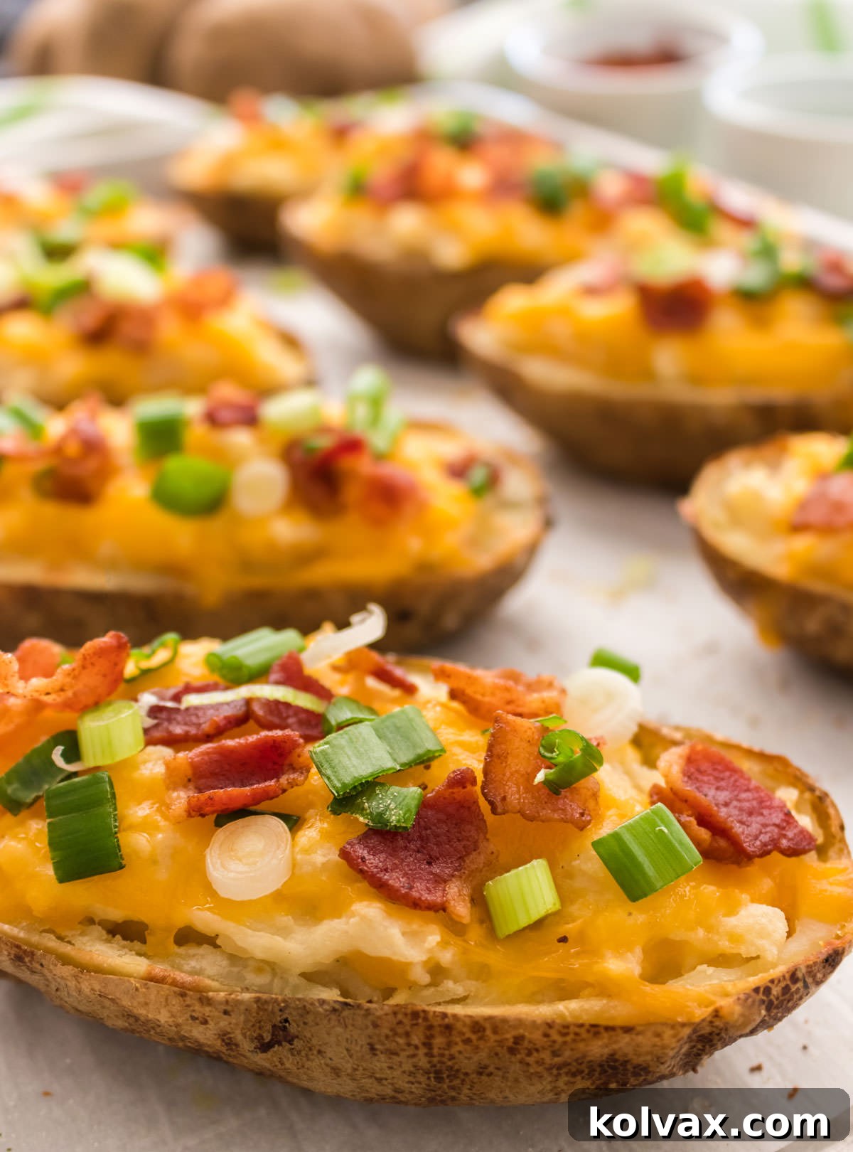 Creamy Stuffed Potato Perfection 7 Closeup of eight Twice Baked Potatoes sitting on a cookie sheet surrounded by white ramekins filled with bacon and green onion.