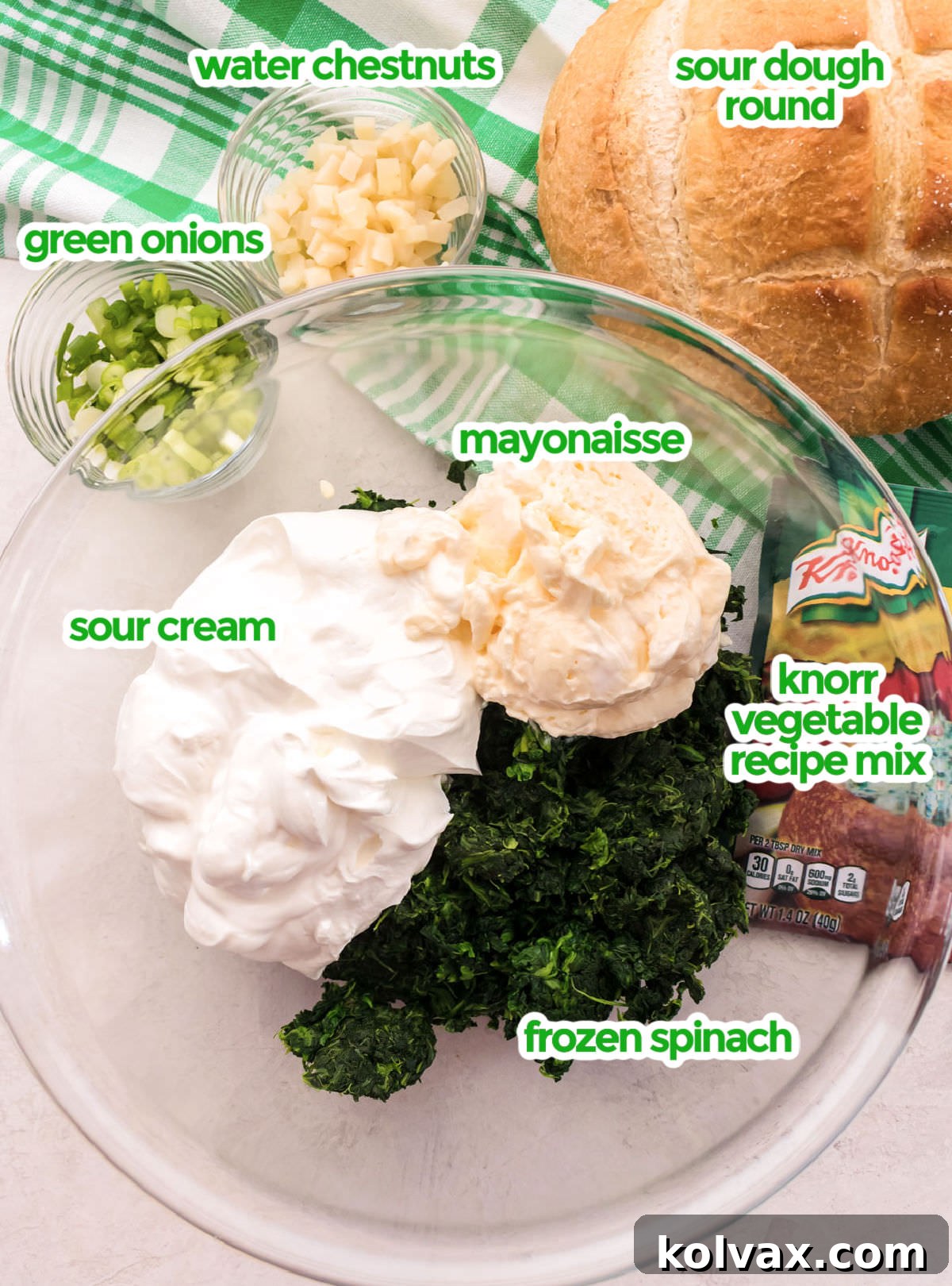 All the ingredients you will need to make Creamy Spinach Dip, including frozen spinach, sour cream, mayonnaise, Knorr vegetable recipe mix, green onions, water chestnuts, and a sourdough round.