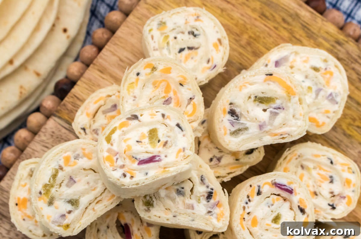 Closeup on a stack of Tortilla Pinwheels sitting on a cutting board next to a stack of flour tortillas, showcasing their vibrant colors and perfect spiral.