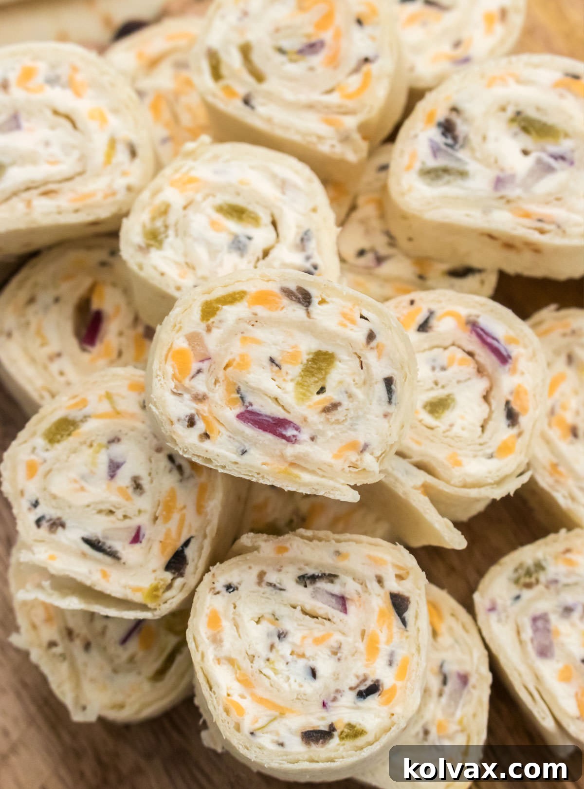 Closeup on a stack of freshly sliced Tortilla Pinwheels sitting on a cutting board, ready to be served.