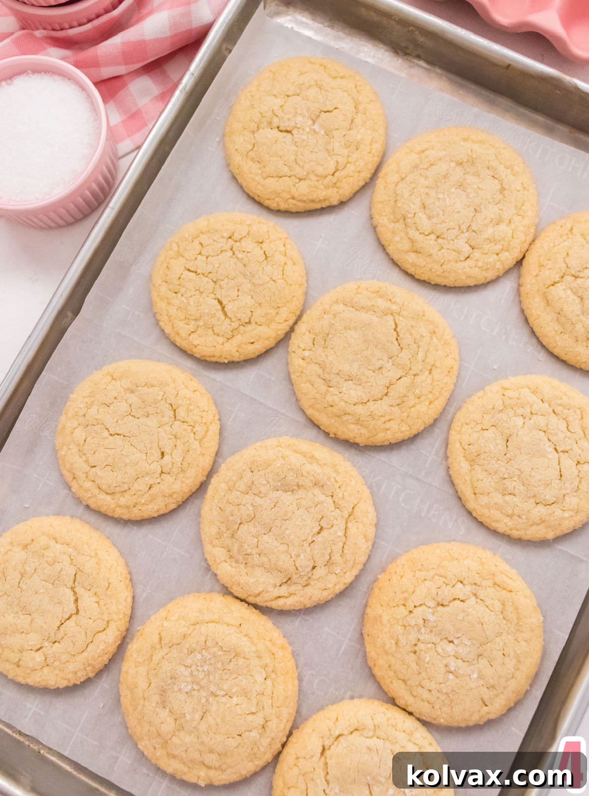 Closeup of a dozen Soft and Chewy Sugar Cookies just out of the oven on a cookie sheet lined with parchment paper.