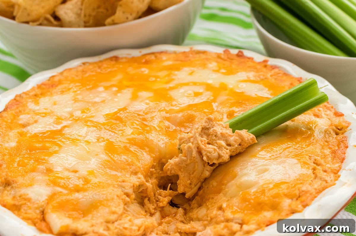 Close-up of a round ceramic pie plate filled with warm, bubbling Buffalo Chicken Dip, richly covered in melted, golden-brown cheese and ready to serve.