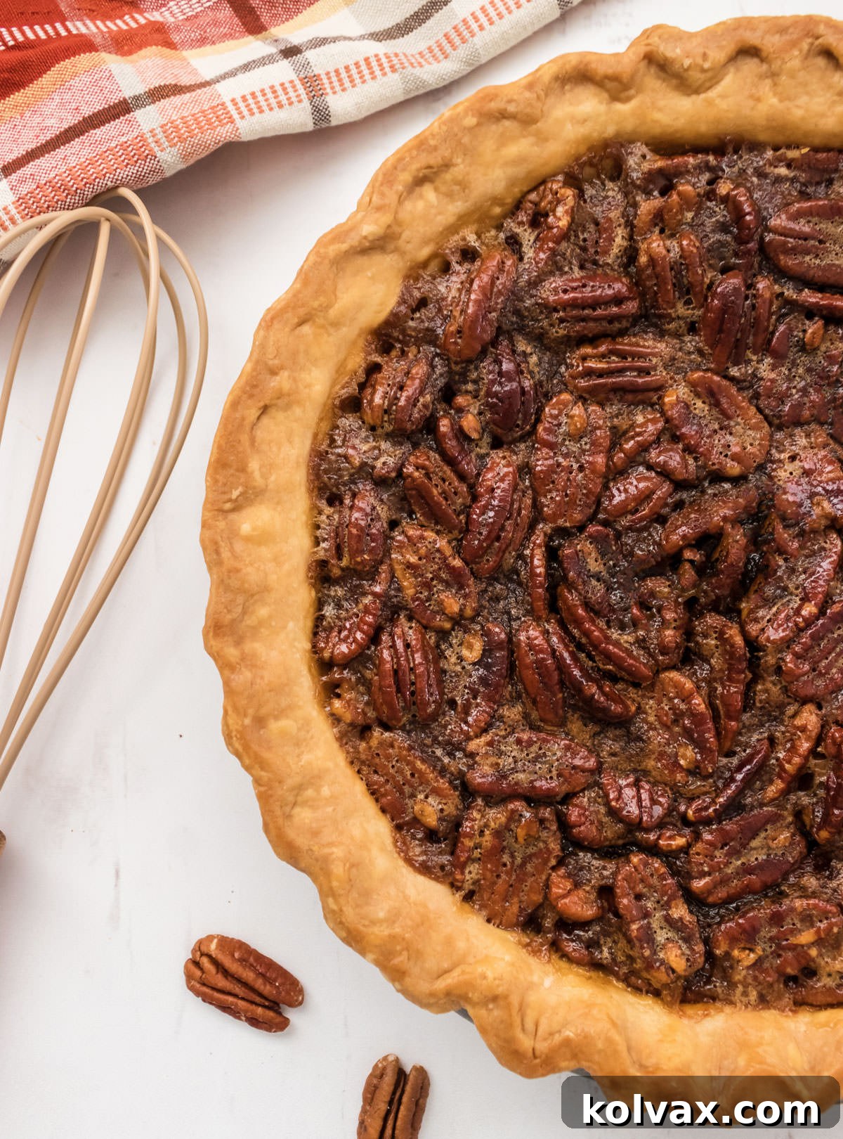 Half of a fully baked, beautiful pecan pie resting on a white marble surface, ready to be sliced and served.