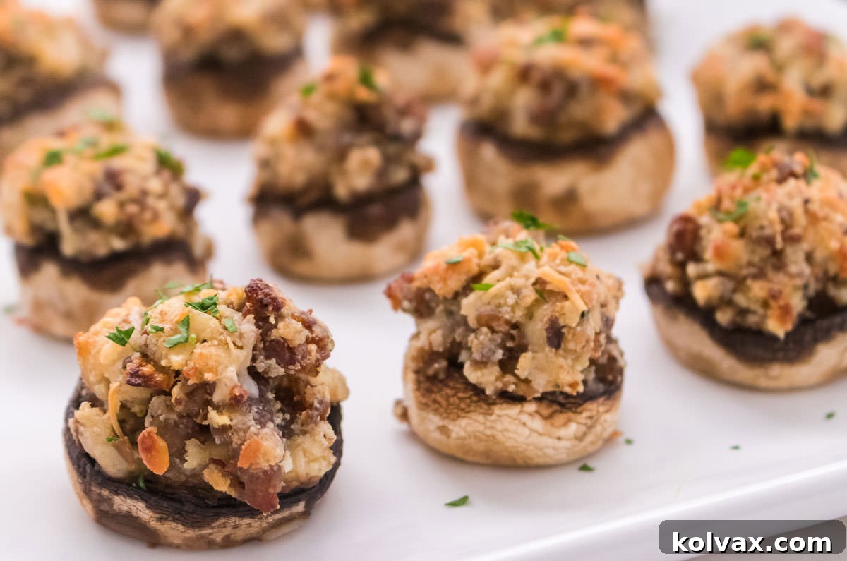Closeup on a dozen Stuffed Mushrooms neatly arranged on a parchment-lined baking sheet, ready for the oven.