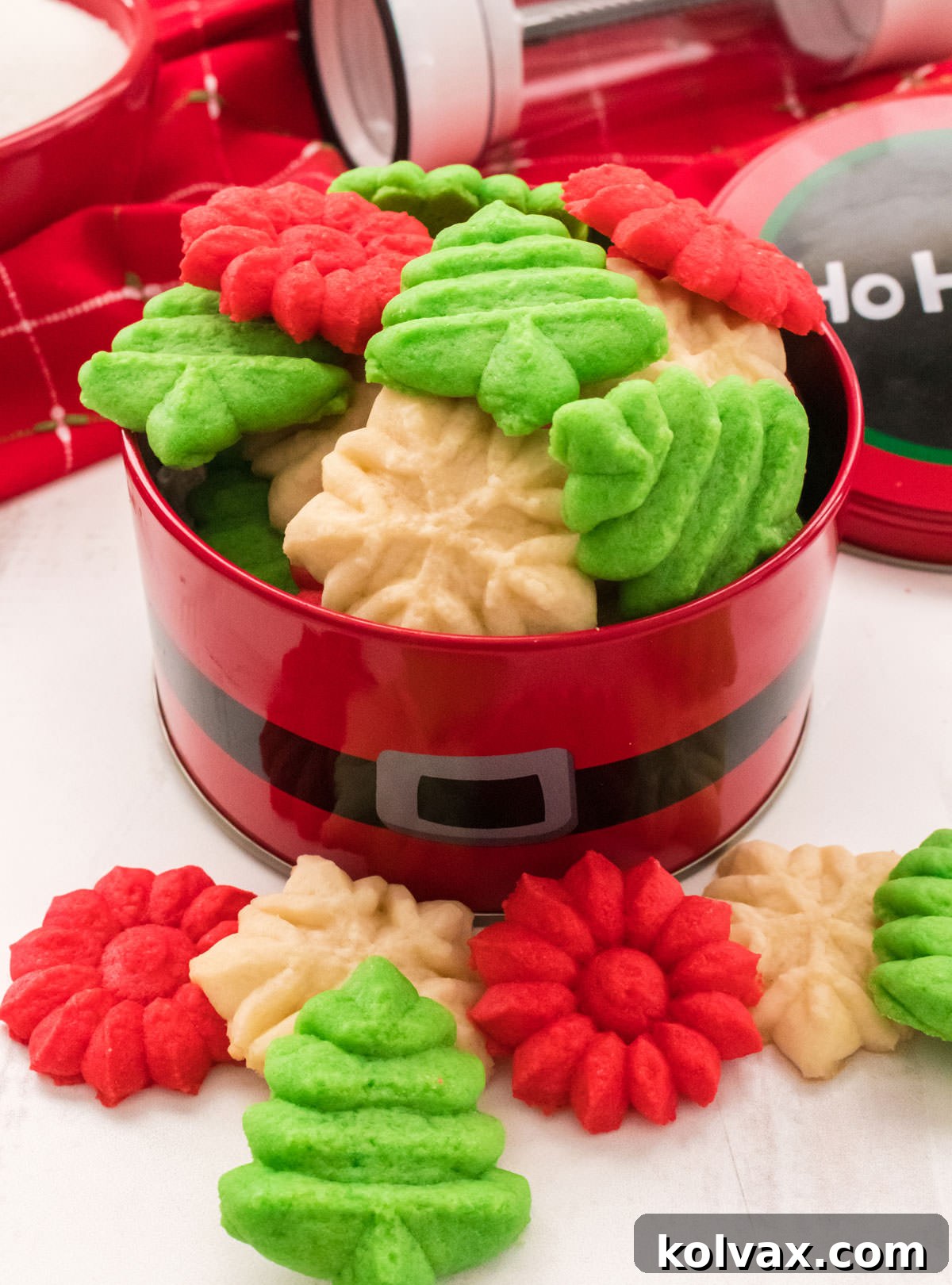 A close-up of beautifully baked Spritz Cookies in red, white, and green nestled in a festive Christmas tin, ready for gifting or serving.