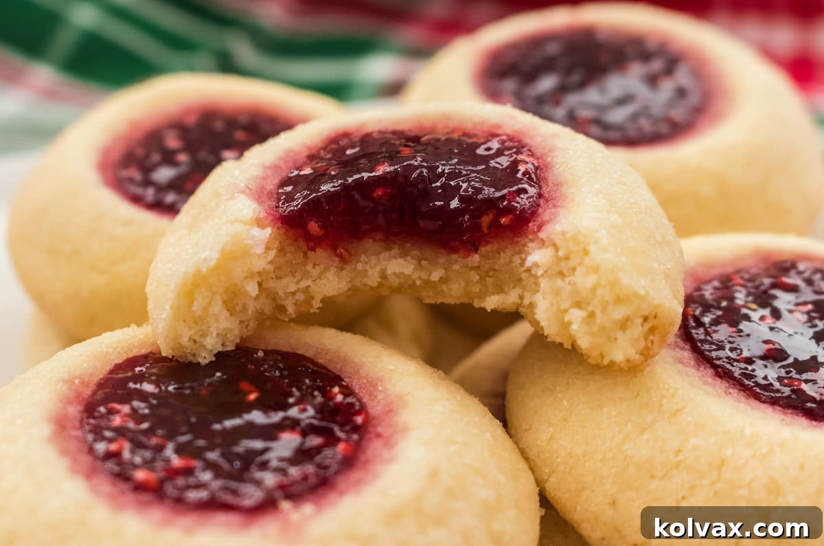 Close-up of a stack of Thumbprint Cookies with one of the cookies with a bite out of it.