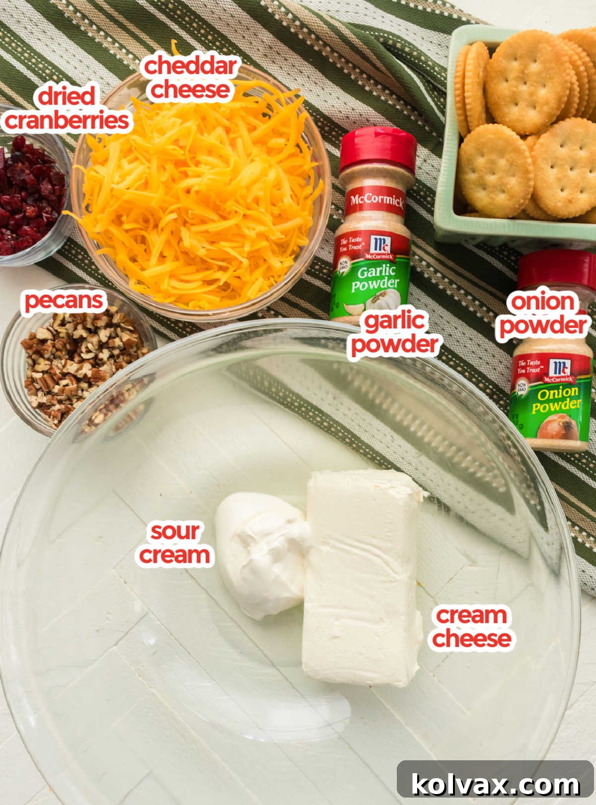 Essential ingredients for a homemade Pecan Cheese Ball: cream cheese, shredded cheddar, sour cream, garlic powder, onion powder, and chopped pecans and cranberries.