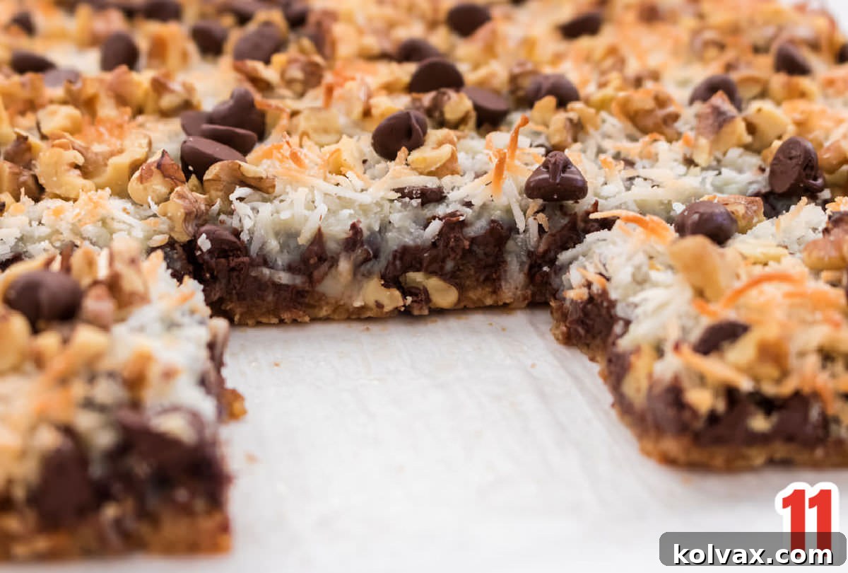 Cooled Magic Bars being neatly cut into individual cookie bar servings, showcasing the distinct layers.