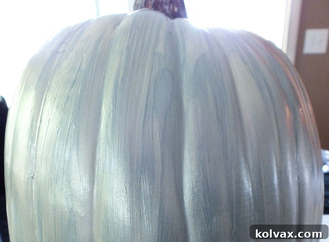 First coat of metallic silver paint on a fake pumpkin
