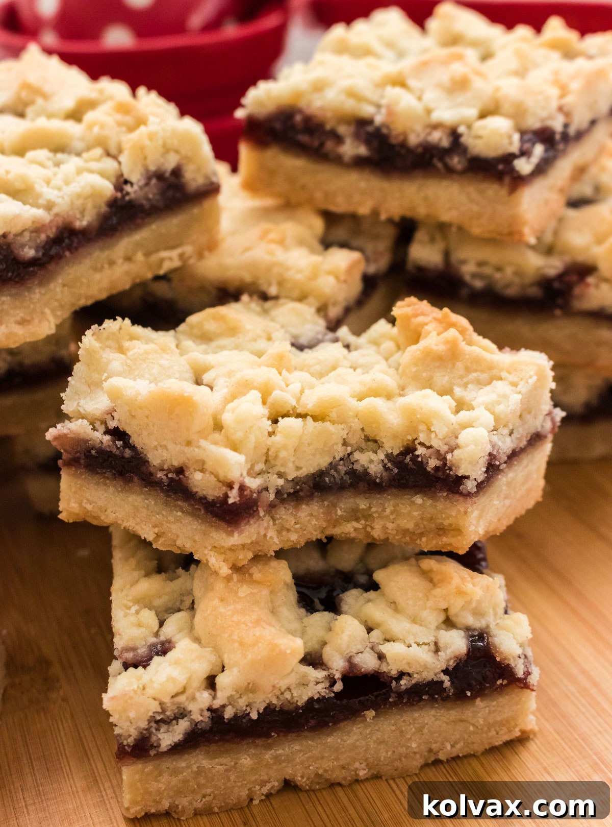 A close-up view of a stack of Shortbread Cookie Bars, with one bar having a bite taken out, revealing the luscious, sweet jam center against the buttery shortbread.