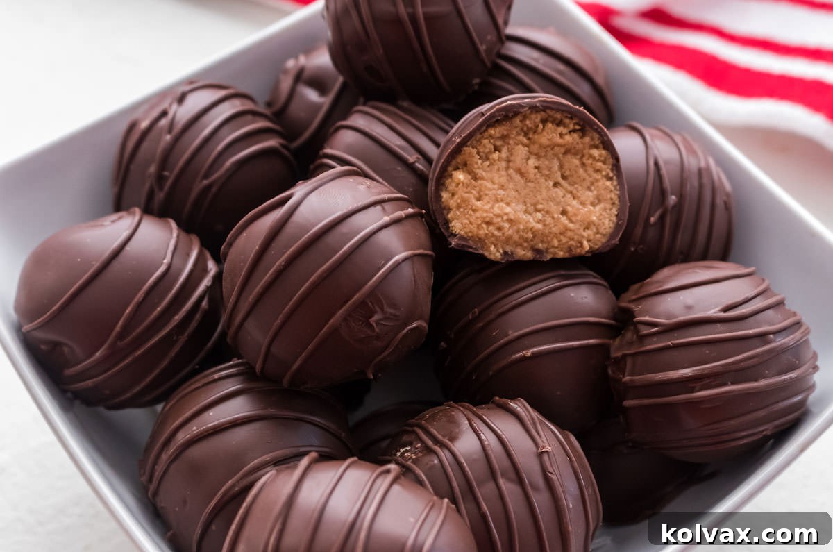 Close up of a white bowl filled with Peanut Butter Candies including one candy that is cut in half to showing the peanut butter filling.