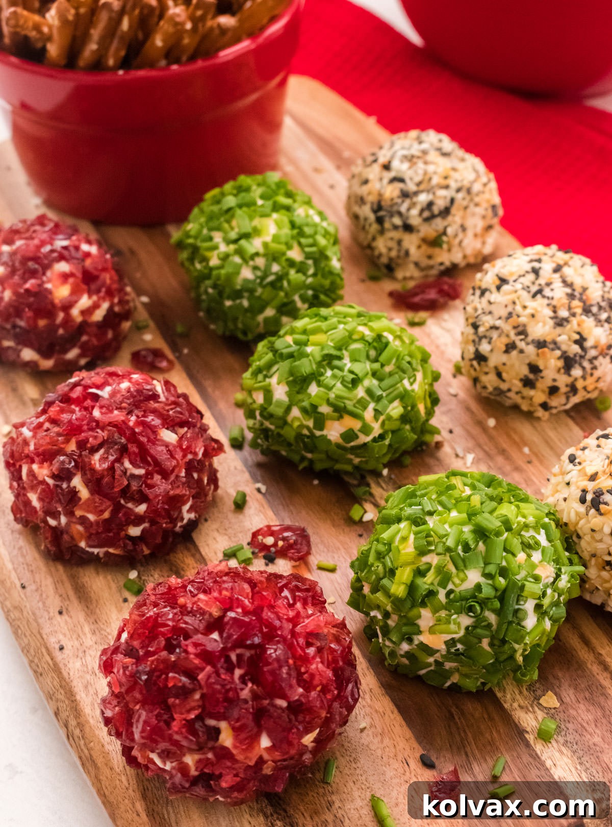 Golden Cheese Puffs 7 A festive display of Mini Cheese Ball Bites resting on a wooden cutting board, with a red ramekin full of pretzel sticks in the background, ready for guests to enjoy.