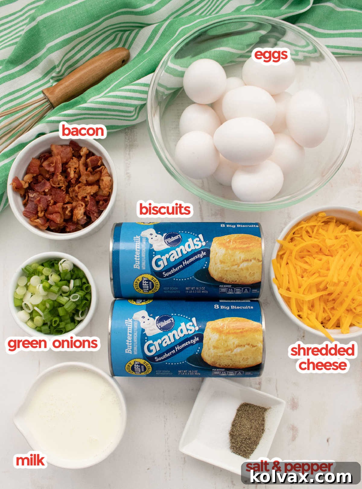 Ingredients needed for the Bacon and Egg Breakfast Casserole: refrigerated biscuits, fresh eggs, milk, shredded cheddar cheese, crisp bacon, and chopped green onions displayed on a kitchen counter.