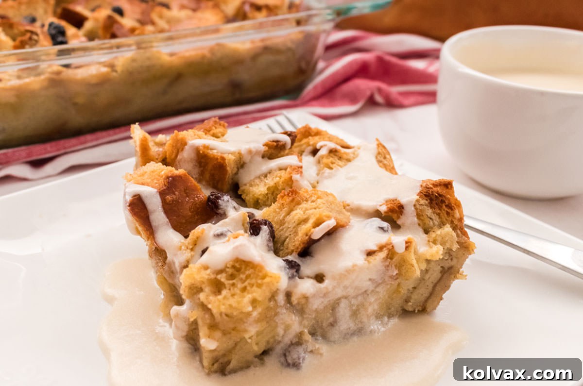 Delicious traditional bread pudding with a rich vanilla custard, topped with raisins and a creamy vanilla sauce, served warm for a classic comfort dessert.