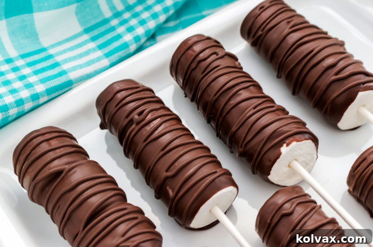 Close up on a white platter holding four decadent Chocolate Marshmallow Pops with an aqua kitchen linen in the background, showcasing their delicious coating and potential for beautiful decoration.