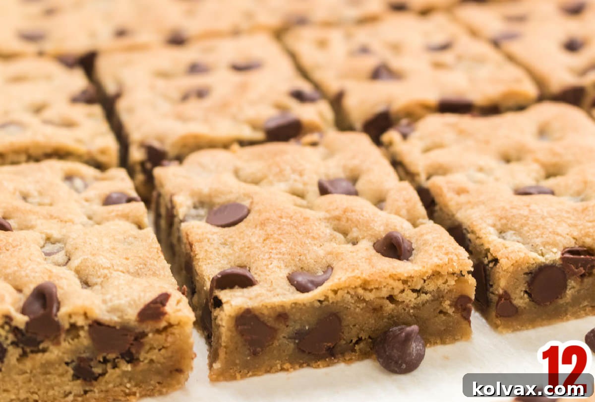 A neat row of individually cut, golden-brown Chocolate Chip Cookie Bars arranged on a clean white surface, showcasing their perfect shape and inviting texture.