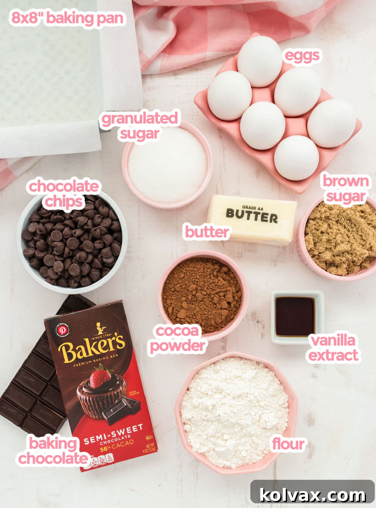 All the ingredients needed to make Homemade Fudge Brownies including eggs, sugar, chocolate bar, cocoa powder, chocolate chips, butter, vanilla and flour, neatly arranged on a counter.