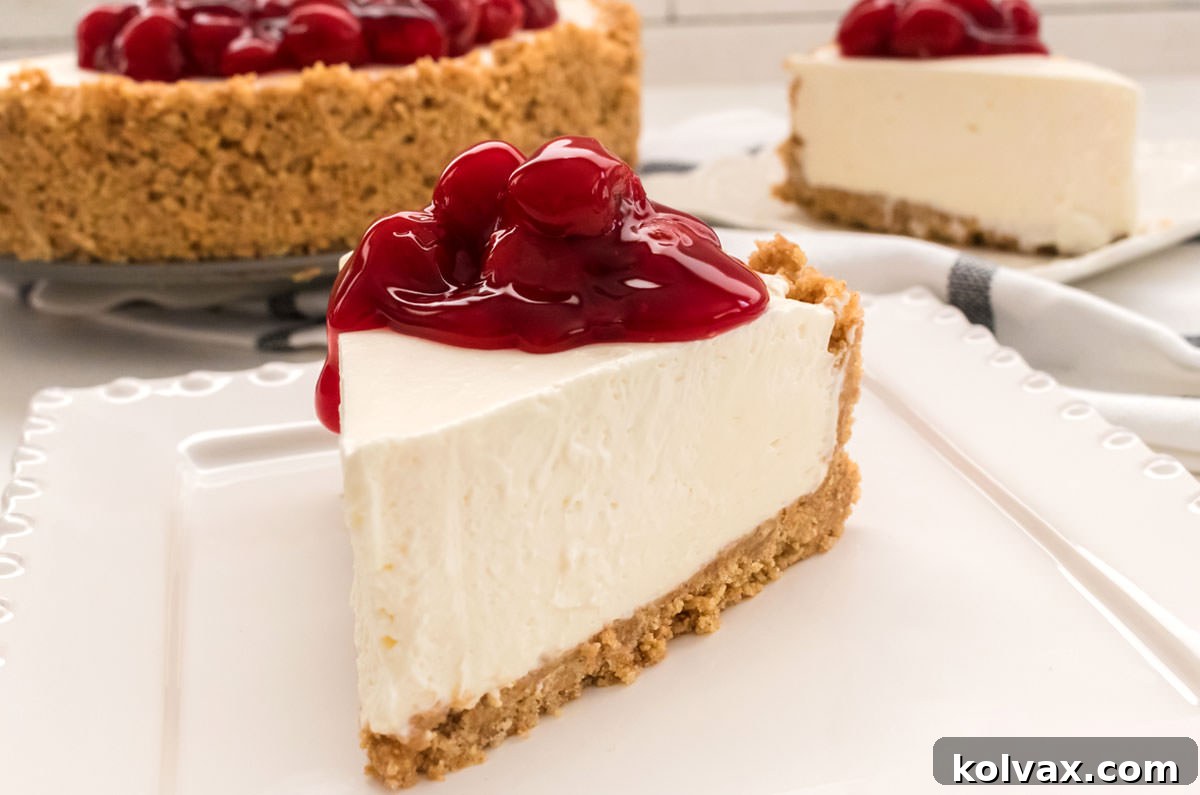 Closeup on a single slice of no-bake cheesecake, generously topped with vibrant cherry pie filling, showcasing its smooth, creamy texture and golden crumbly crust.