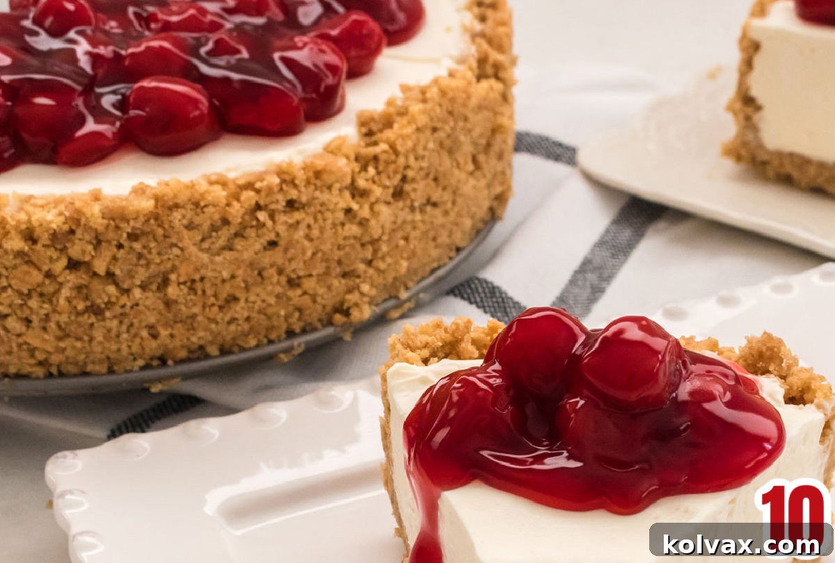 Closeup shot of the luscious cherry pie filling perfectly topping a portion of the set no-bake cheesecake, highlighting its vibrant color and tempting texture.