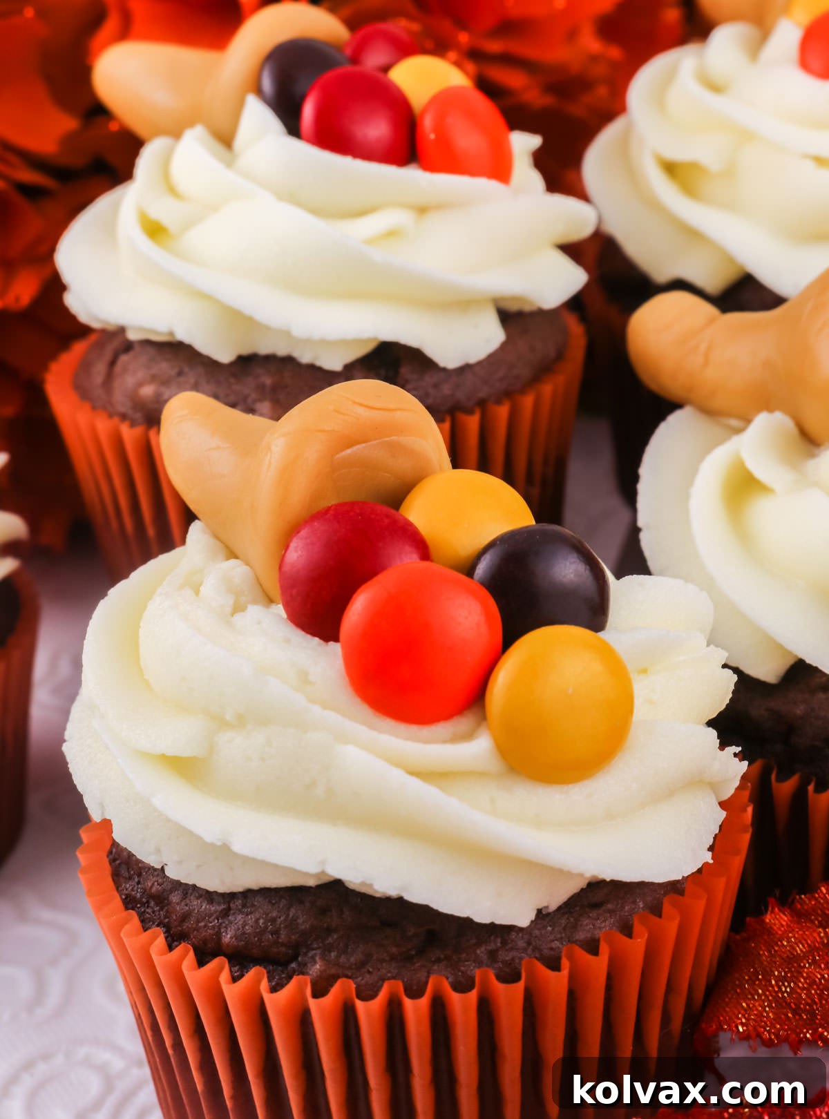Closeup on a Caramelcopia Thanksgiving Cupcake sitting on a white surface surrounded by other cupcakes.