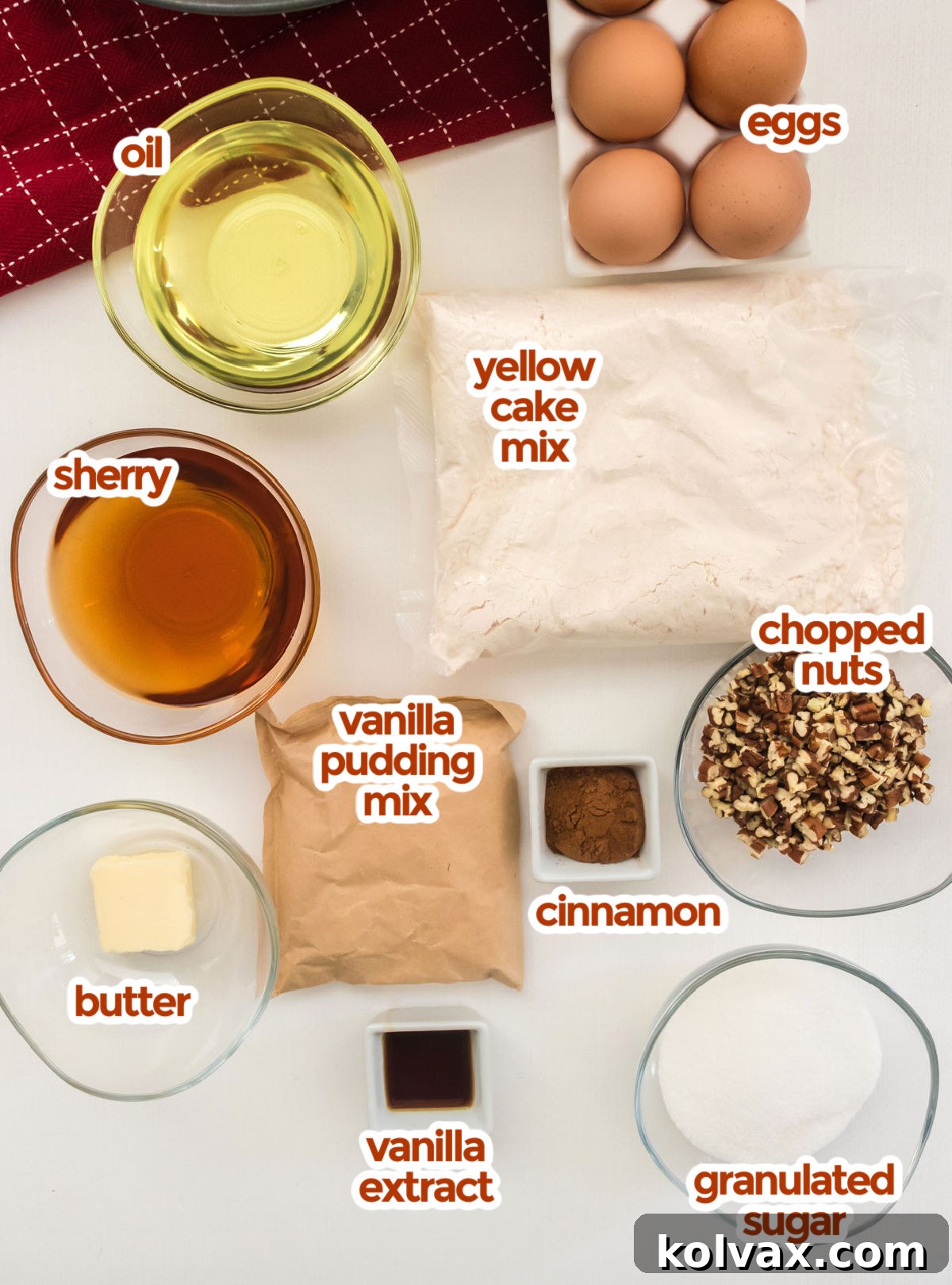 Yuletide Morning Coffee Cake 3 A flat lay photograph displaying all the ingredients needed for Christmas Morning Coffee Cake: yellow cake mix, eggs, oil, sherry, chopped nuts, vanilla pudding mix, cinnamon, butter, vanilla extract, and granulated sugar.