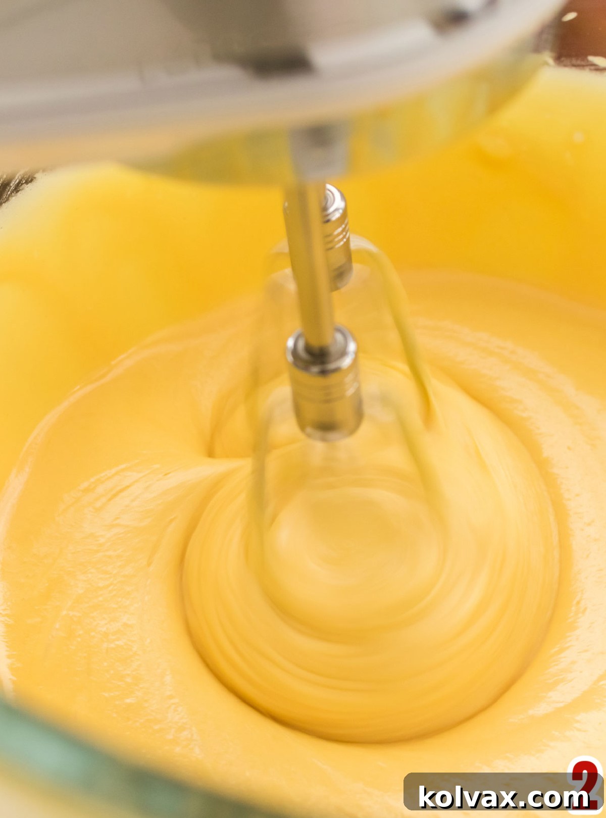 Yuletide Morning Coffee Cake 5 A hand mixer actively blending the Christmas Morning Coffee Cake batter in a glass bowl, creating a smooth and airy consistency.