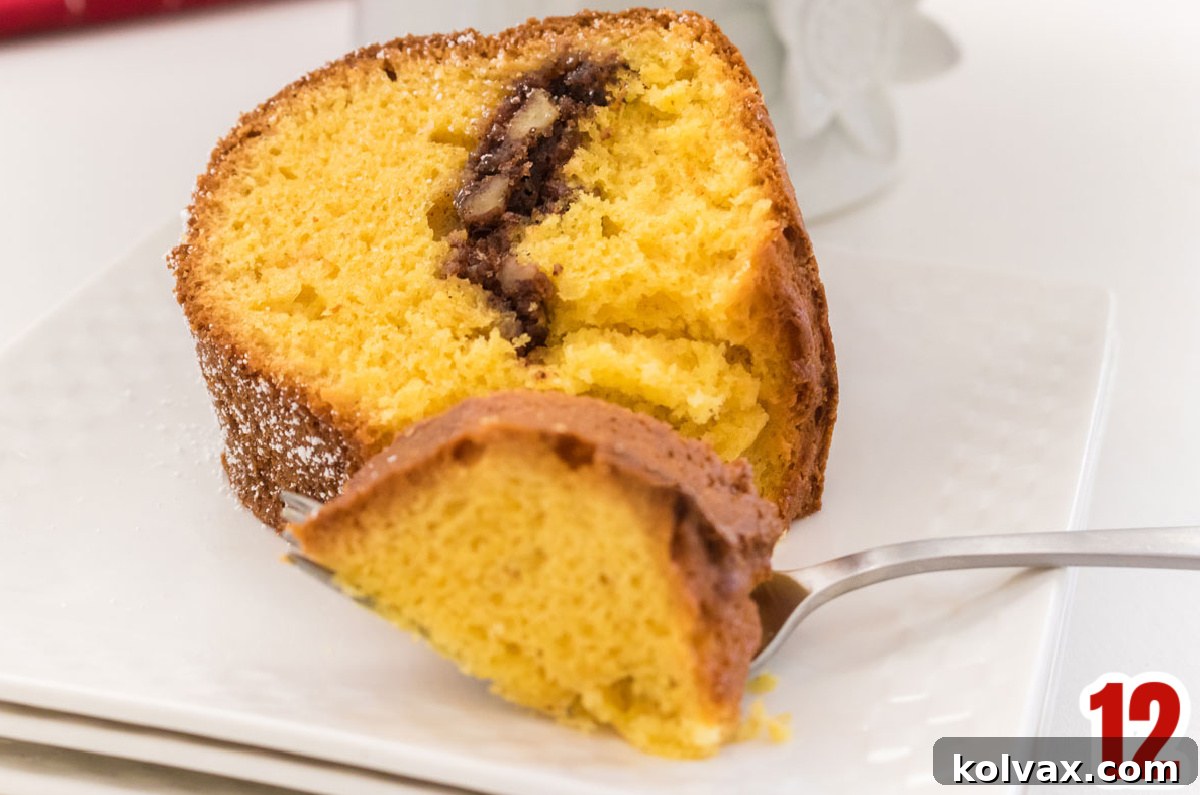 Yuletide Morning Coffee Cake 9 A close-up shot of a slice of Sherry Cake on a white plate, revealing the intricate layers of moist cake and cinnamon-sugar filling, accompanied by a fork.