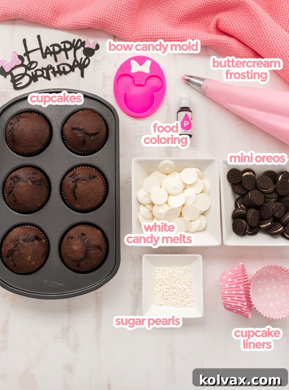All the essential ingredients for Minnie Mouse Cupcakes including chocolate cupcakes, pink buttercream frosting, white candy melts, mini Oreos, a bow mold, and sugar pearls.