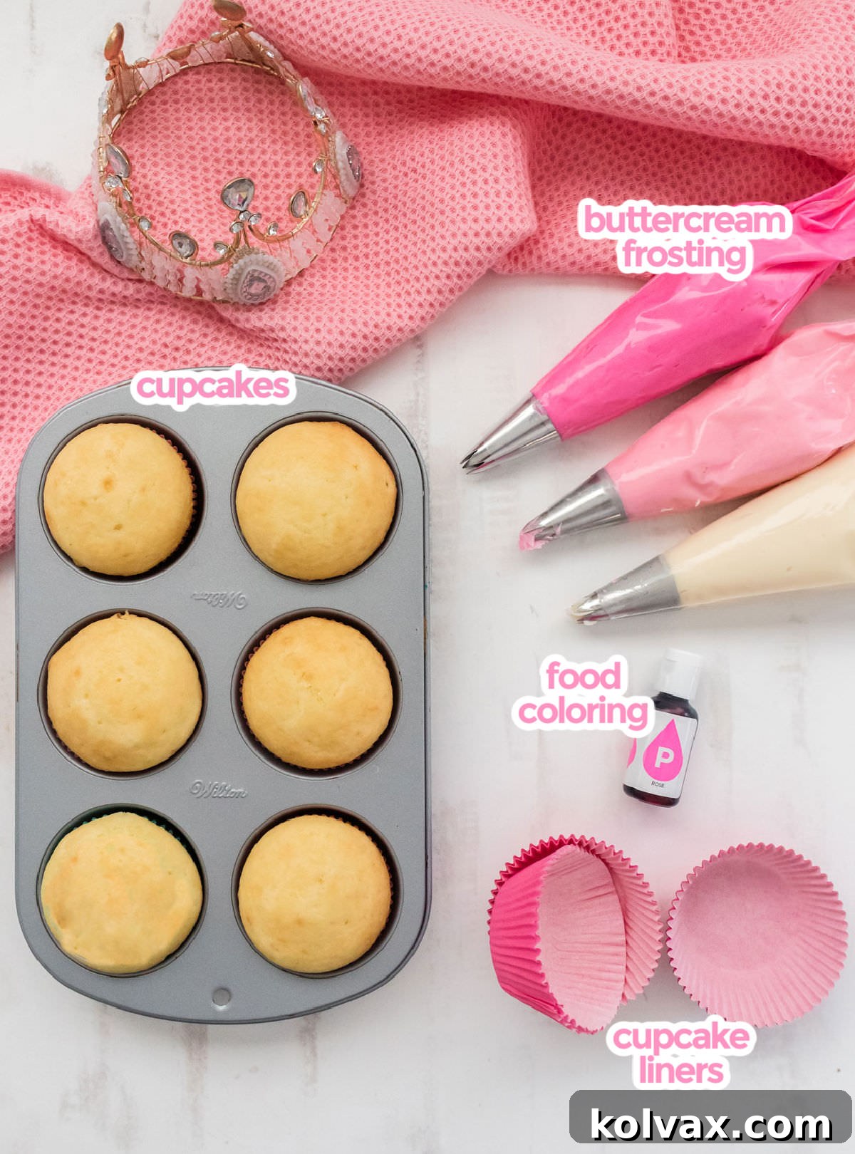 A flat lay showing all the essential ingredients for Princess Cupcakes, including a box of cake mix, prepared pink buttercream frosting, various food coloring tubes, and decorative cupcake liners, all ready for baking.