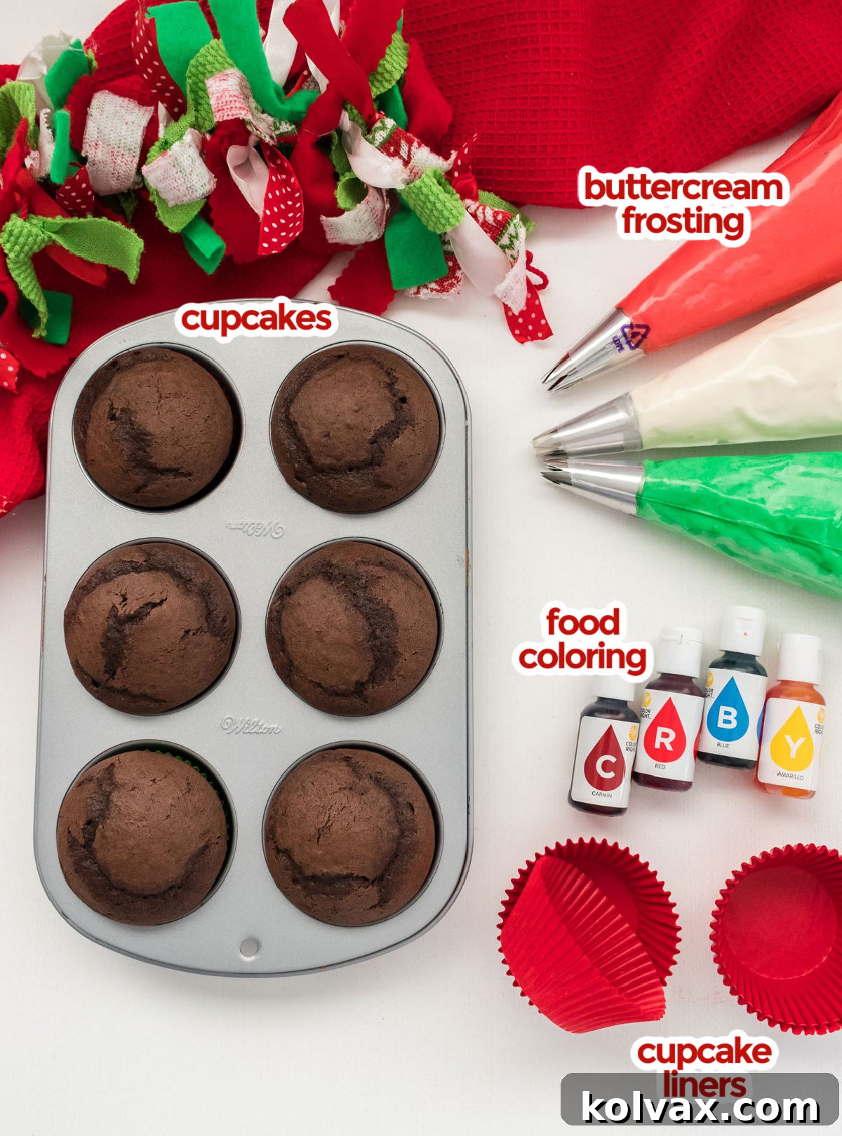 A vibrant flat lay displaying all the necessary ingredients for crafting Easy Christmas Cupcakes, including a box of cake mix, prepared buttercream frosting, various food colorings, and festive red cupcake liners, set on a bright white surface with holiday sprinkles.